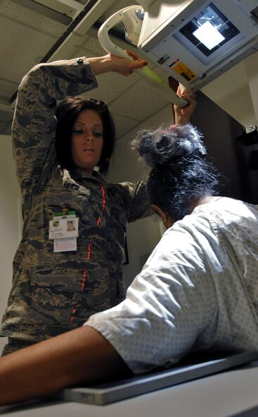 U.S. Air Force Senior Airman Kelly Tipps, 7th Medical Support Squadron diagnostic imaging technician, adjusts an X-ray machine to better scan patient Sylvia Urban March 14, 2014, at Dyess Air Force Base, Texas. Diagnostic imaging technicians operate fixed and portable diagnostic imaging equipment to produce diagnostic medical images. (U.S. Air Force photo by Senior Airman Peter Thompson/Released)