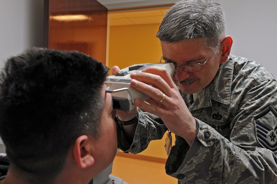 U.S. Air Force Master Sgt. Mathew Daughtry, right, 7th Aerospace Medicine Squadron optometry certified paraoptometric technician, evaluates Tech. Sgt. Stephen Burgin’s eyes, 7th Munitions Squadron, March 14, 2014, at Dyess Air Force Base, Texas. Optometry is the healthcare profession concerning the health of the eyes and related structures, including vision and visual information processing systems. (U.S. Air Force photo by Senior Airman Peter Thompson/Released)