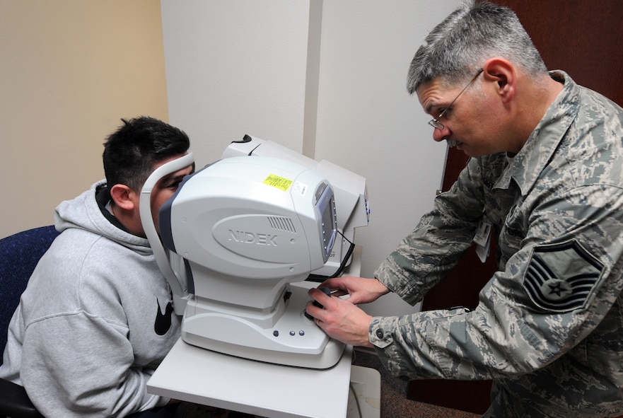 U.S. Air Force Master Sgt. Mathew Daughtry, right, 7th Aerospace Medicine Squadron optometry certified paraoptometric technician, evaluates Tech. Sgt. Stephen Burgin’s eyes, 7th Munitions Squadron March 14, 2014, at Dyess Air Force Base, Texas. The Optometry Clinic provides eye health examinations for Team Dyess. (U.S. Air Force photo by Senior Airman Peter Thompson/Released)