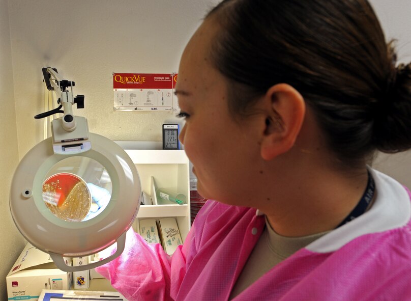 U.S. Air Force Senior Airman Malissa Ross, 7th Medical Support Squadron medical laboratory assistant, examines a throat culture plate March 14, 2014, at Dyess Air Force Base, Texas. The recovery and identification of disease causing microorganisms allows providers to start treatment and stop the contagious bug from spreading to others. (U.S. Air Force photo by Senior Airman Peter Thompson/Released)