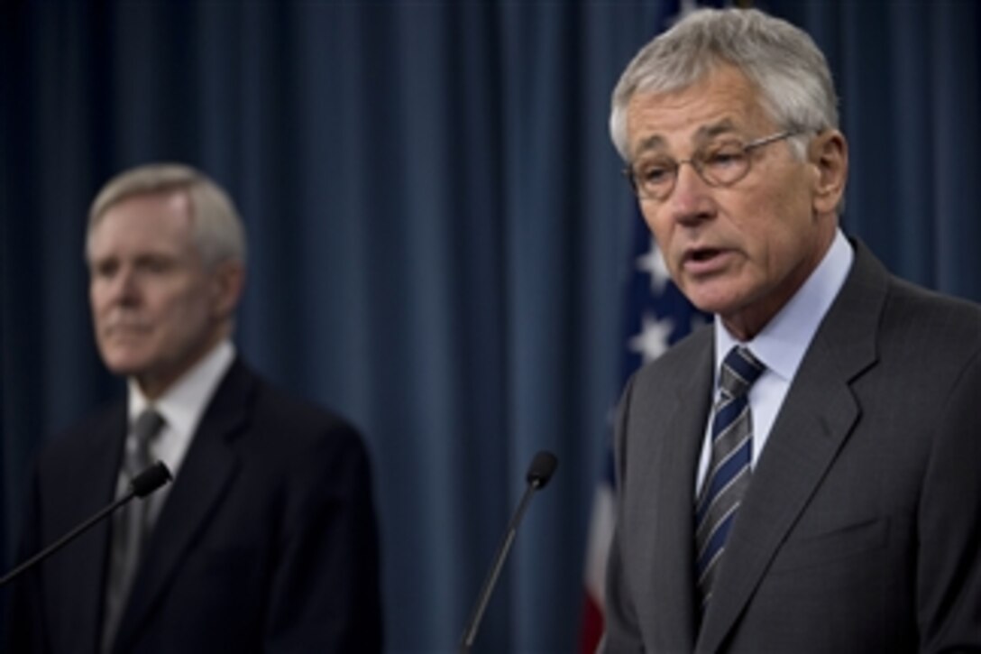 Defense Secretary Chuck Hagel delivers remarks as Navy Secretary Ray Mabus looks during a briefing at the Pentagon, March 18, 2014. Hagel and Mabus addressed plans to implement changes following the Washington Navy Yard shooting investigations and reviews. During the Sept. 16, 2013, shooting, a civilian contractor killed 12 employees and wounded several others at the Naval Sea Systems Command headquarters building before being killed by police.