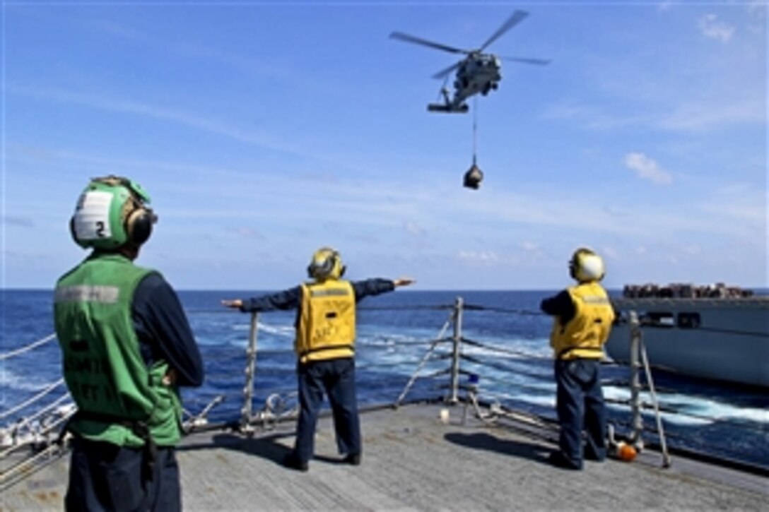 U.S. sailors use hand signals while directing helicopter operations onboard the destroyer USS Kidd at sea, March 17, 2014, as it assists in search operations for missing Malaysia Airlines Flight 370. 