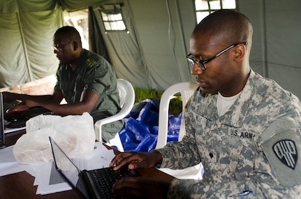 Congolese national police Capt. Patrick Ossate and Spc. Daren E. Mills from the New York Army National Guard's 369th's Sustainment Brigade process Soldiers March 18 arriving at Exercise Central Accord 14 in Douala, Cameroon, March 18, 2014. The two are part of the Joint Reception, Staging, Onward movement and Integration cell, which manages personnel arriving and departing the exercise.