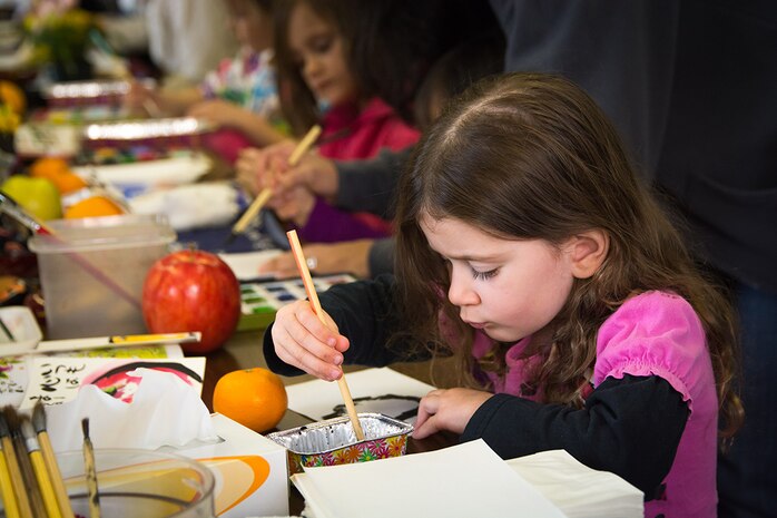 Attendees of the Japanese American Society Culture Festival practice writing Japanese calligraphy inside the Matthew C. Perry High School cafeteria aboard Marine Corps Air Station Iwakuni, Japan, March 8, 2014. The free festival allowed station residents to participate in multiple events including Ikebana flower arrangement, origami and Japanese calligraphy.