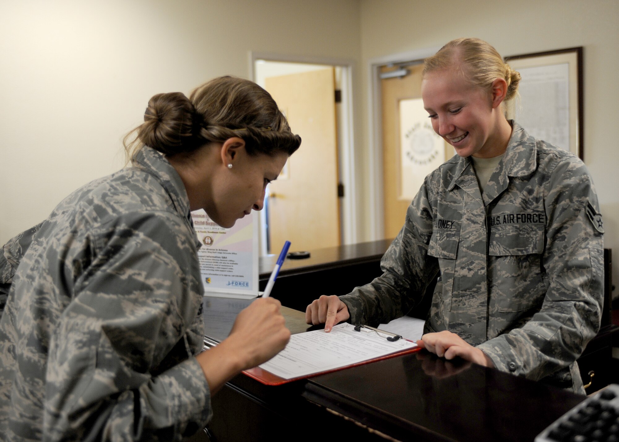 U.S. Air Force Airman 1st Class Molly Moloney, 355th Fighter Wing general law paralegal, helps a customer fill out an intake sheet in the 355th FW legal office, Davis-Monthan Air Force Base, Ariz., March 19, 2014. During her off-duty time Moloney works out to prepare for fitness competitions. (U.S. Air Force photo by Airman 1st Class Cheyenne Morigeau/ Released)