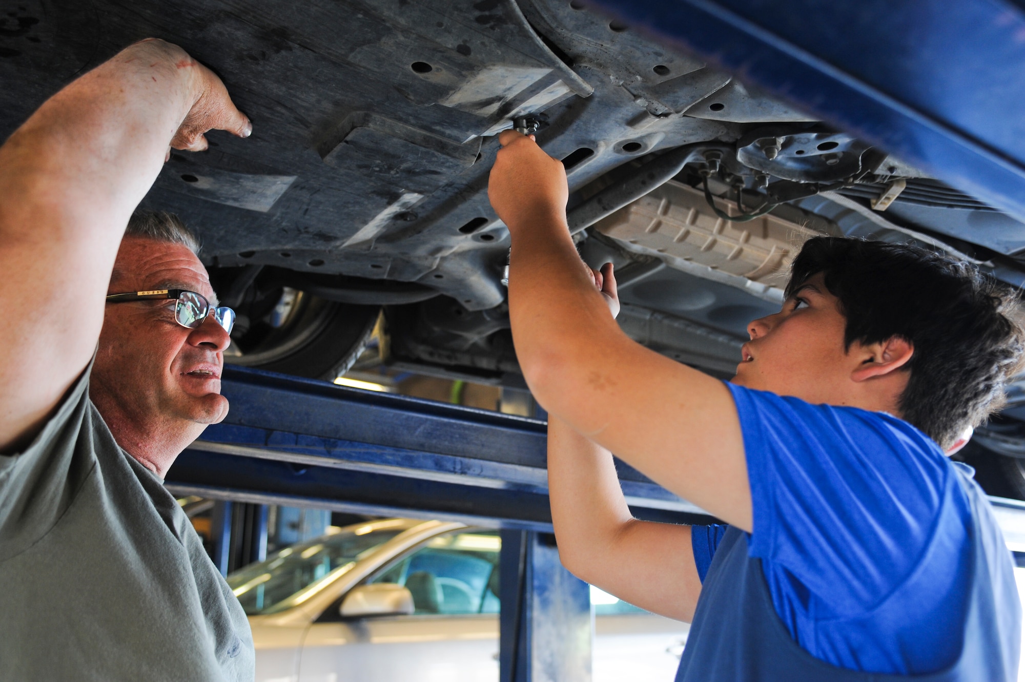 Steve Nichols, Auto Hobby Shop customer, teaches his son Chris Carney, the different steps of changing the oil at Davis-Monthan Air Force Base, Ariz., March 18, 2014. The bays are booked on a first-come-first-serve basis and a member can either make the repairs themselves or request assistance from a mechanic. (U.S. Air Force photo by Senior Airman Sivan Veazie/Released)