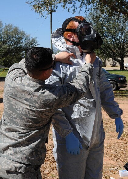 Airman 1st Class Alexander Trippett, 2nd Civil Engineer Squadron Explosive Ordnance Disposal technician, assists Staff Sgt. Timothy Ostberg, 2nd CES EOD technician, with donning a chemical suit on Barksdale Air Force Base, La., March 13, 2014.  EOD Airmen participated in an exercise that simulated a detonation of a risin dispersal device which may, or may not have contained chemicals. (U.S. Air Force photo/Senior Airman Joseph A. Pagán Jr.)