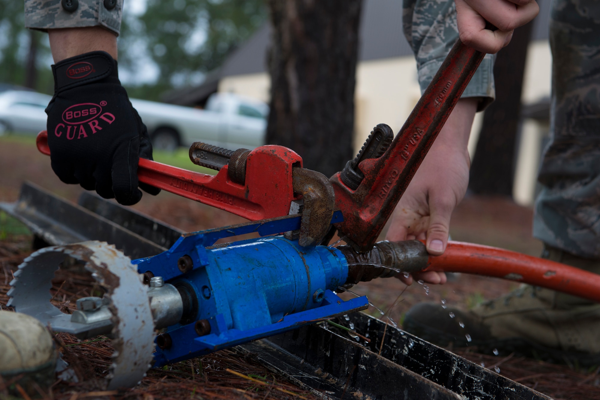 U.S. Air Force Senior Airman Robert Kost and Airman 1st Class Ryan Morris, 23d Civil Engineer Squadron water and fuel system maintenance technicians, place a cutter attachment to the water hose at Moody Air Force Base, Ga., March 18, 2014. The cutter is used to break up any additional clogs in the sewage drain pipes after the jetter is used. (U.S. Air Force photo by Airman Dillian Bamman/Released)