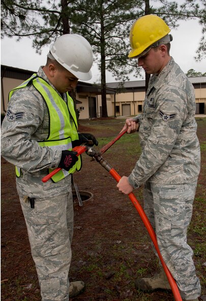 U.S. Air Force Senior Airman Robert Kost and Airman 1st Class Ryan Morris, 23d Civil Engineer Squadron water and fuel system maintenance technicians, remove a jetter from the water hose at Moody Air Force Base, Ga., March 18, 2014. The jetter shoots high-pressured water to break up excessive plumbing blockage. (U.S. Air Force photo by Airman Dillian Bamman/Released)