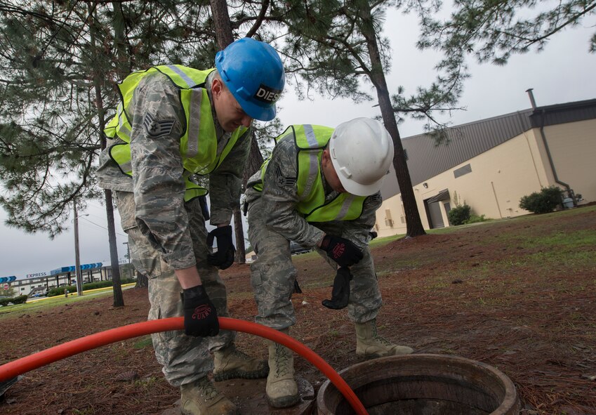 U.S. Air Force Staff Sgt. Trevor Loken and Senior Airman Robert Kost, 23d Civil Engineer Squadron water and fuel system maintenance technicians, inspect a sewer drain for clogs at the 23d Logistics Readiness Squadron at Moody Air Force Base, Ga., March 18, 2014. The building needed maintenance after experiencing plumbing issues due to the clogging. (U.S. Air Force photo by Airman Dillian Bamman/Released)