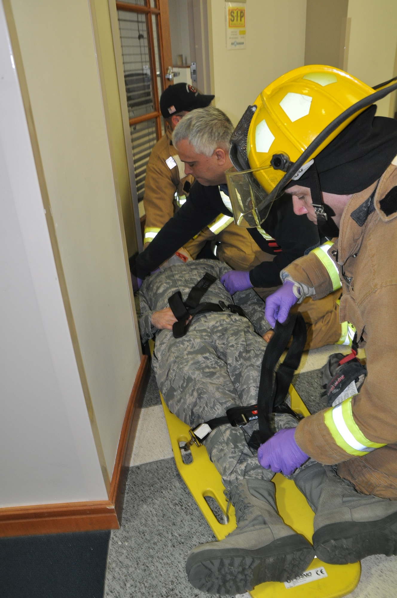 Youngstown Air Reserve Station firefighters secure a simulated gunshot victim to a stretcher during an active shooter training exercise here, March 18, 2014. The purpose of the base-wide exercise was to identify and correct response weaknesses, ensuring safety and security of personnel and property. (U.S. Air Force photo/Major Brent Davis)