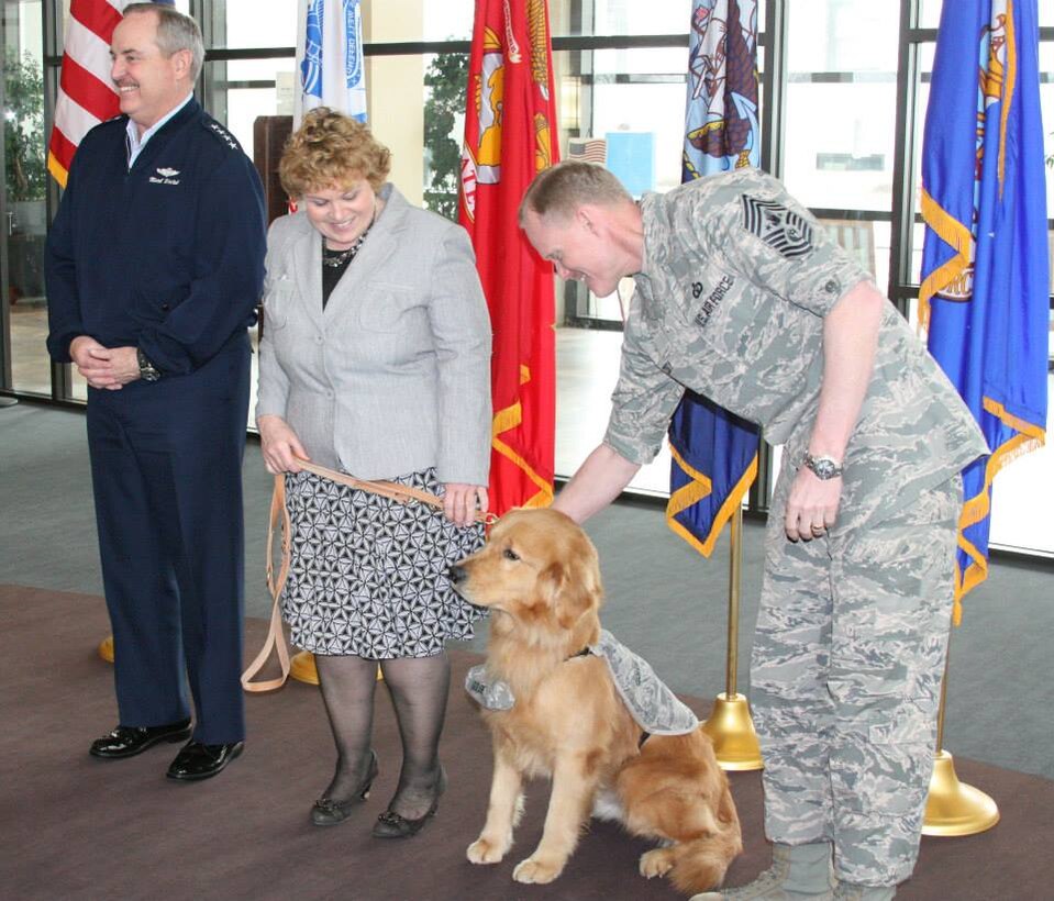 Chief Master Sgt. of the Air Force James A. Cody, the highest ranking enlisted member in the U.S. Air Force, pats Goldie, held by Patty Barry, coordinator of the facility dog program at Walter Reed Bethesda, before the Golden Retriever’s commission as a second lieutenant by Air Force Chief of Staff Gen. Mark A. Welsh III (left) on March 12 at Walter Reed National Military Medical Center. (Photo by Bernard S. Little)
