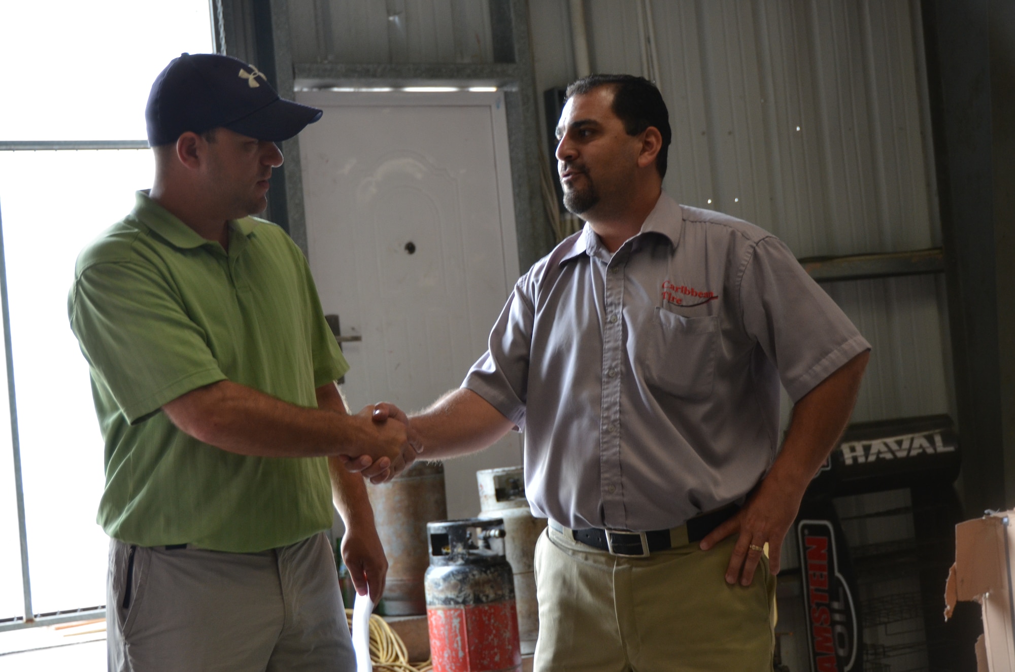 Tech. Sgt. Ryan Schnepf, New Horizons contracting officer, shakes hands with the manager of a local tire repair shop after coming to a purchase account agreement March 13. Contracting officials will be working with several local businesses throughout the exercise. (U.S. Air Force photo by Master Sgt. Kelly Ogden/Released)