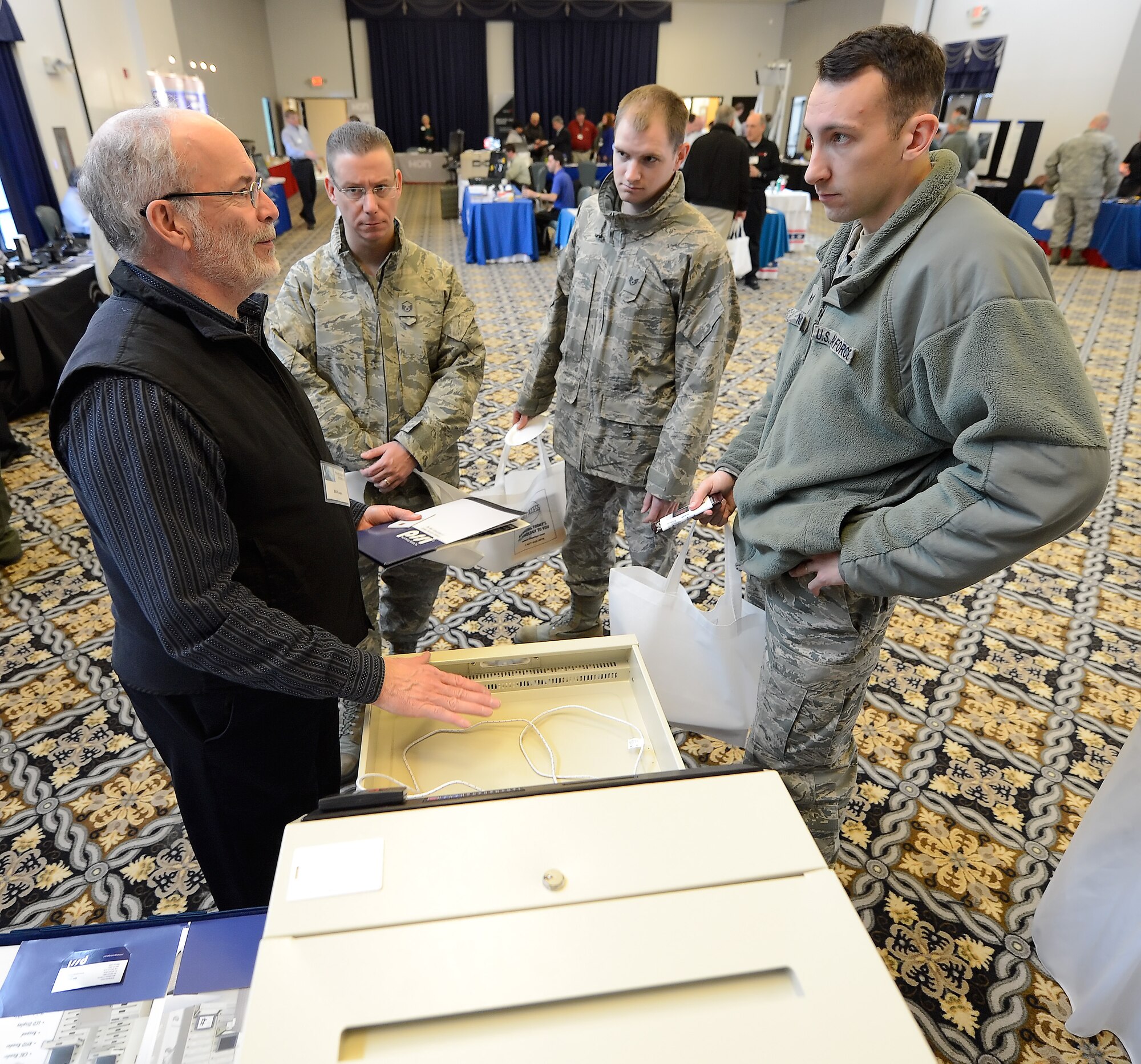 Bill Powers, left, points out some features of a lockable storage cabinet to members of the 436th Communications Squadron during the 2014 Dover Air Force Base Technology Exposition at The Landings Club, March 18, 2014, at Dover Air Force Base, Del. Powers is the sales manager for Plug-In Storage Systems, Inc. which specializes in securing high-value equipment such as laptops. (U.S. Air Force photo/Greg L. Davis)