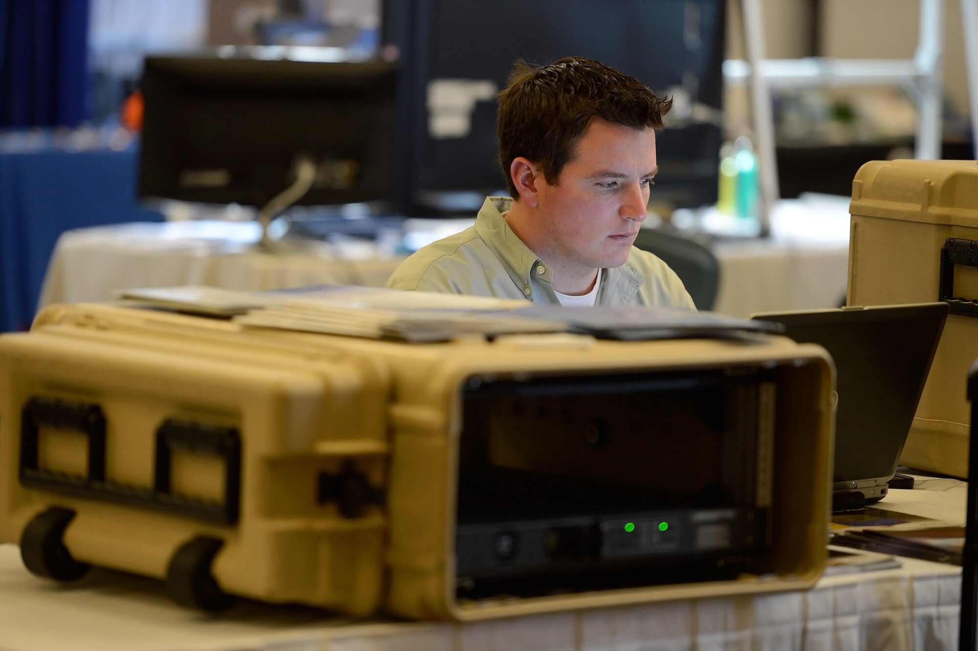 Michael Klug of Integral Marketing works on his laptop computer positioned between ruggedized cases his company sells at the 2014 Dover Air Force Base Technology Exposition at The Landings Club, March 18, 2014, at Dover Air Force Base, Del. The expo was hosted by the 436th Communications Squadron to allow exhibitors to showcase their products with potential customers from across the base. (U.S. Air Force photo/Greg L. Davis)