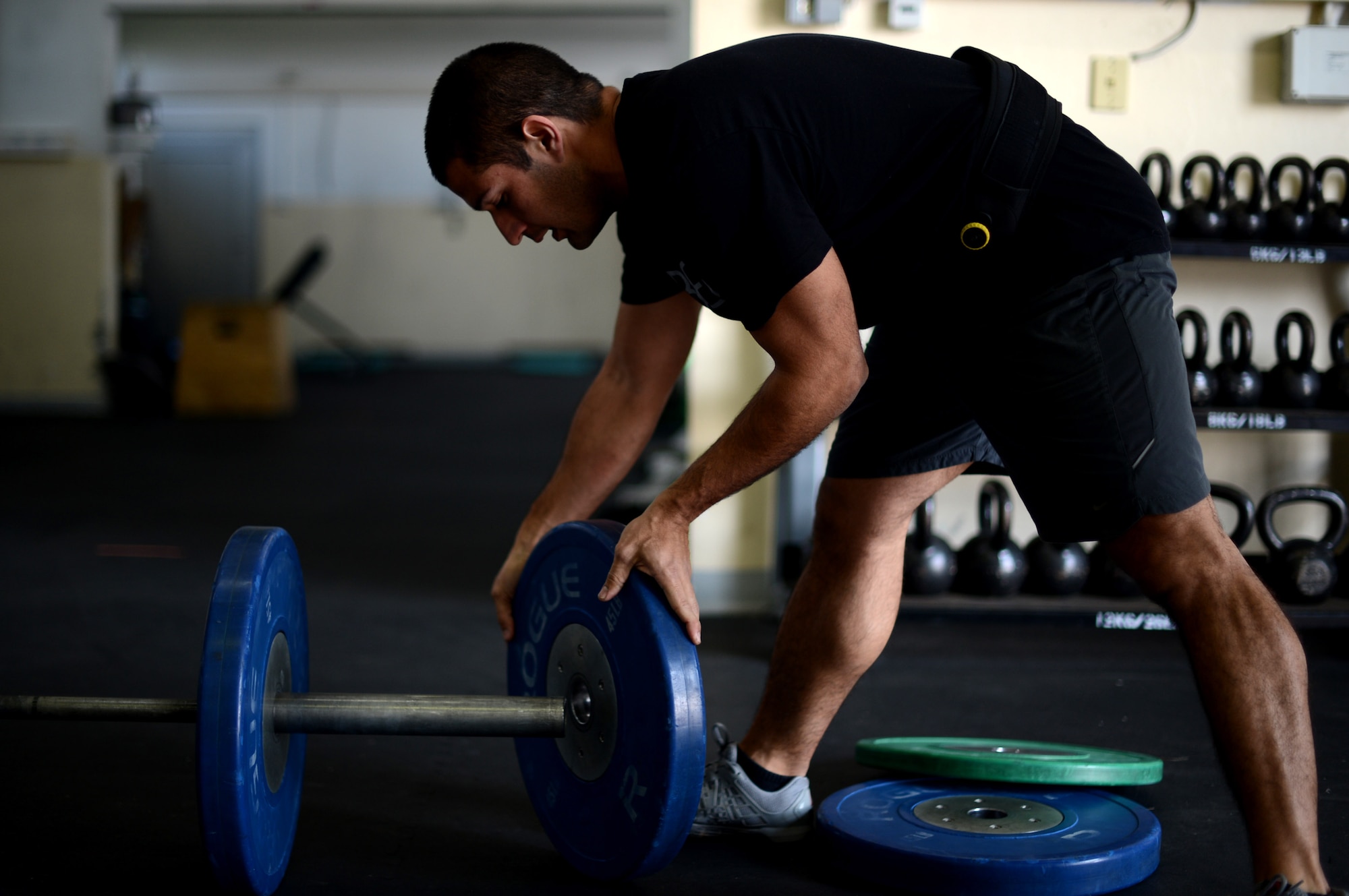 U.S. Air Force Senior Airman Anthony Pelaez, 52nd Component Maintenance Squadron jet engine mechanic from Miami, loads a 45-pound weight to a barbell at Spangdahlem Air Base, Germany, March 14, 2014. Comprehensive Airmen fitness is made up of four categories: physical, mental, emotional and spiritual fitness. (U.S. Air Force photo by Airman 1st Class Kyle Gese/Released)