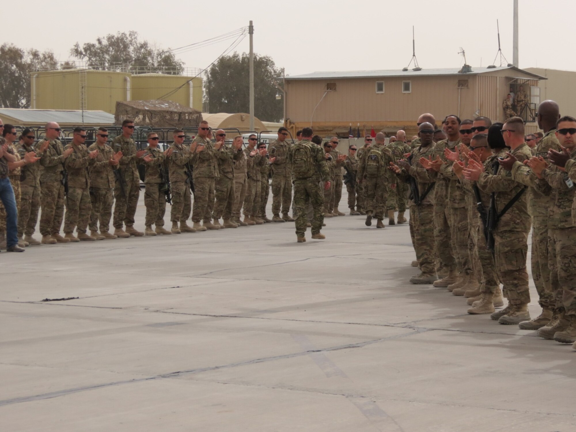 Service members from all branches of service line up along the flightline at Kandahar Airfield, Afghanistan, to honor and applaud five soldiers severely injured in the line of duty during the fifth edition of Operation Proper Exit, March 13, 2014. Troops First Foundation hosts the operation with an objective of bringing recovered soldiers back to the theater to build a brotherhood with current deployed troops and well as provide closure in leaving the war zone on their own terms. (U.S. Air Force photo by Senior Airman Alexandria Bandin/Released)