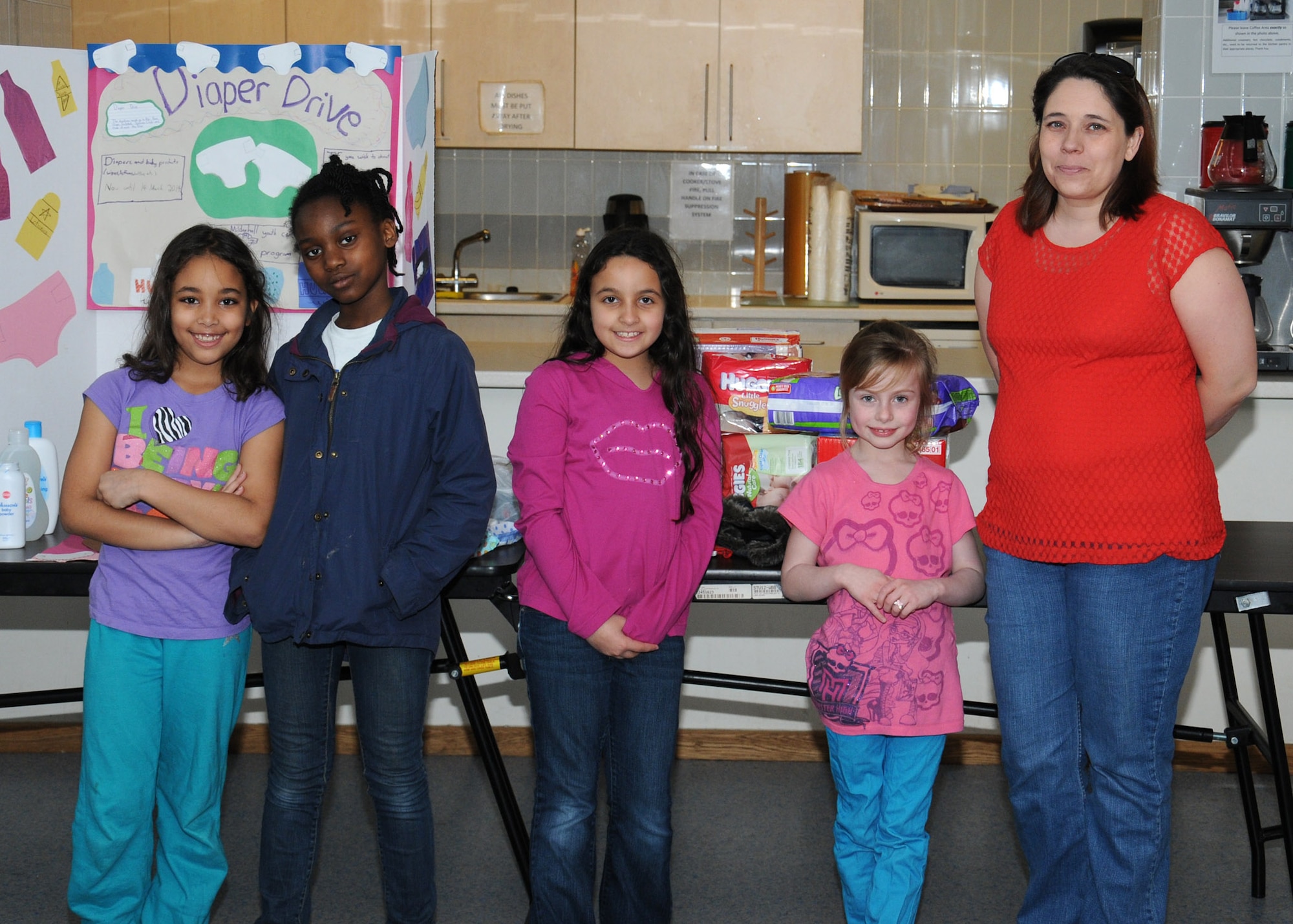 Misty Villarin, right, a member of the RAF Mildenhall enlisted spouses club, and from left, Samantha Benson, Aniya Johnson, Chloe Reyes and Caelyn Glab, from the RAF Mildenhall Youth Center, pose for a photo during a diaper drive March 14, 2014, in the chapel on RAF Mildenhall, England. Parents of children from the youth center and child development center donated diapers and clothing. The items are going to be donated to Team Mildenhall spouses during the upcoming enlisted spouse baby shower. (U.S. Air Force photo by Gina Randall/Released)
