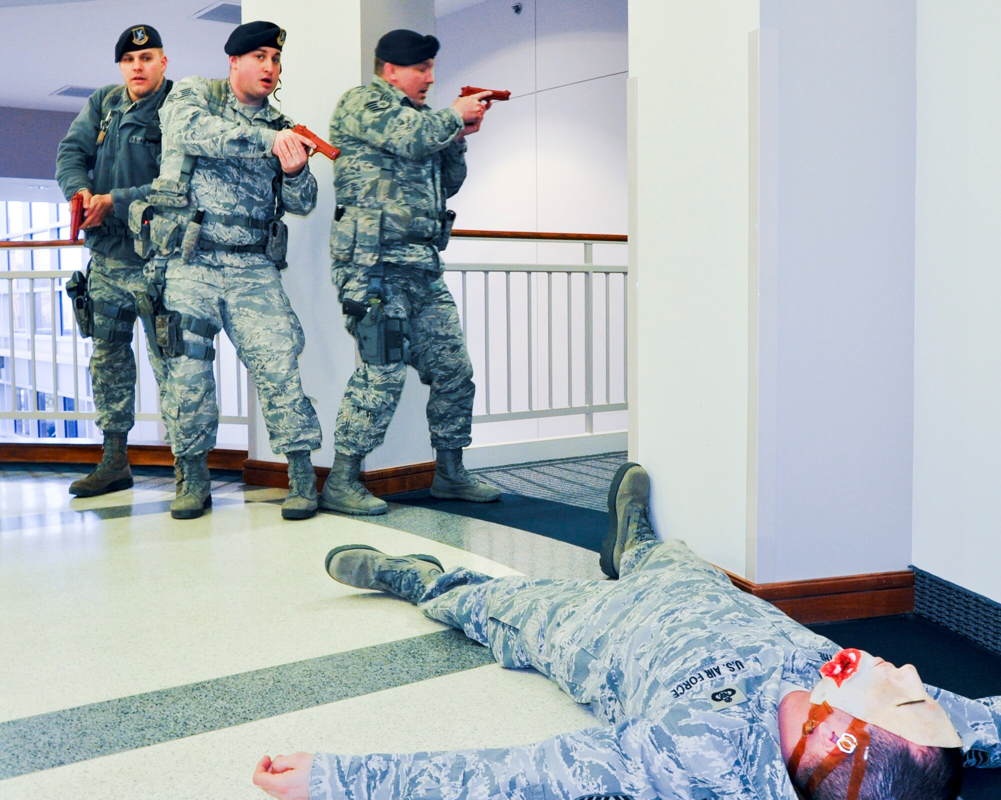 A 910th Security Forces Squadron fire team sweeps the wing headquarters building in search of an active shooter during a training exercise here, March 18, 2014. A simulated casualty is shown in the foreground. Members of the 910th Airlift Wing regularly participate in exercises like these to test their preparedness. (U.S. Air Force photo/Maj. Brent J. Davis) 