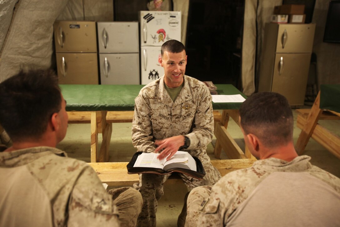 Lieutenant Cmdr. Matthew Berrens, a chaplain with Marine Aircraft Group - Afghanistan, discusses a Bible verse with Marines in a dining facility during a worship service aboard Forward Operating Base Delaram II, Afghanistan, March 13, 2014. Berrens travels around to different combat outposts and forward operating bases to visit and provide spiritual guidance for service members. (U.S. Marine Corps photo by Cpl. Cody Haas/ Released)
