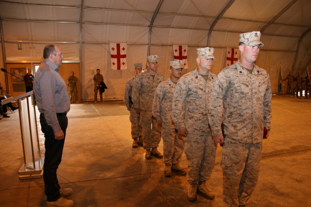 (Front to back) Staff Sgt. Robert Plemmons, Charlie Company Advisor, Georgian Liaison Team 11; Gunnery Sgt. Robert Kaufmann, Alpha Company Advisor, GLT-11; Staff Sgt. Jason Rodriguez, Bravo Company Advisor, GLT-11; 1st Lt. Tyler Ross, Supply and Logistics officer, GLT-11; and Capt. Thomas McCabe, officer in charge, 2nd Air Naval Gunfire Liaison Company, Supporting Arms Liaison Team, prepare to march off after being presented medals by Georgian President Giorgi Margvelashvili, left, during his visit to Camp Leatherneck, Helmand province, Afghanistan, March 15, 2014. During President Margvelashvili's visit, he presented numerous awards to both Georgian soldiers and Marines to show his appreciation for the outstanding work they have accomplished together.
