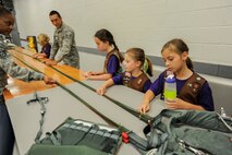 Staff Sgt. Teneil Roman, (left), and Staff Sgt. Juilo Torres, (center), both 15th Operations Support Squadron Aircrew Flight Equipment technicians, explain how pilots use parachutes to eject from aircraft as part of a Girl Scout tour on Joint Base Pearl Harbor-Hickam, Hawaii, March 17, 2014. The girls were on base to participate in a “pilot for-a-day” style career day hosted by the 15th Operations Group, in order to earn the Air Force Pride Badge. (U.S. Air Force photo/Tech. Sgt. Terri Paden)