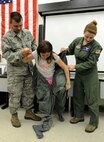 Staff Sgt. Charles Higley, 15th Operations Support Squadron Aircrew Flight Equipment technician, (left) and Capt. Jenny Miller, 535th Airlift Squadron C-17 pilot, (right) help Mia Martin into an anti-exposure suit as part of a Girl Scout tour on Joint Base Pearl Harbor-Hickam, Hawaii, March 17, 2014. Mia joined 26 fellow Brownie Girl Scouts for a “pilot for-a-day” style career day hosted by the 15th Operations Group, in order to earn the Air Force Pride Badge. (U.S. Air Force photo/Tech. Sgt. Terri Paden)