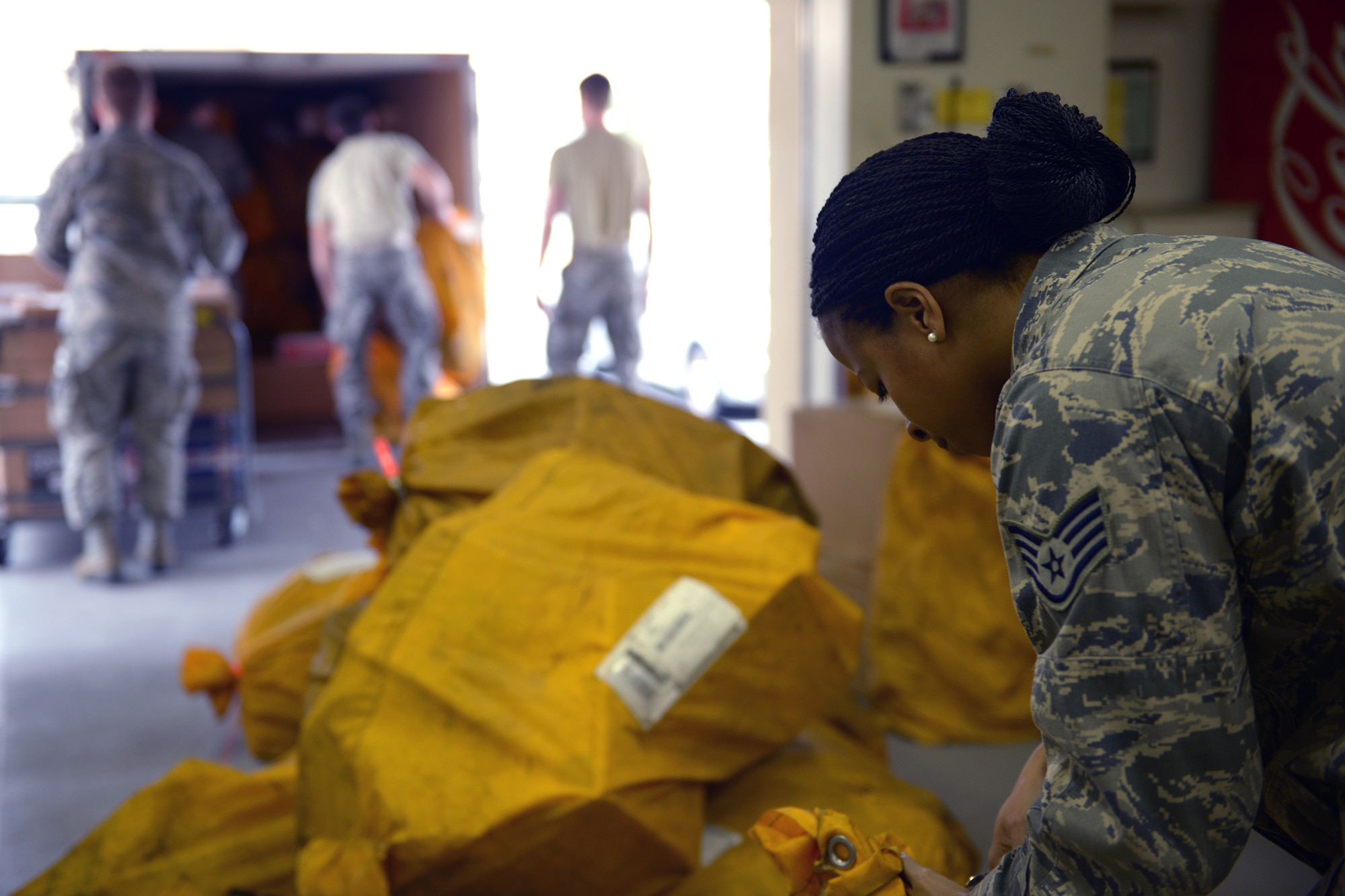 Staff Sgt. Monica Williams, 374th Communications Squadron postal specialist, opens mail bags at Yokota Air Base, Japan, March 19, 2014. The bags are tied to prevent loss of mail during transit in addition to ease of transport. (U.S. Air Force photo by Airman 1st Class David Danford/Released)