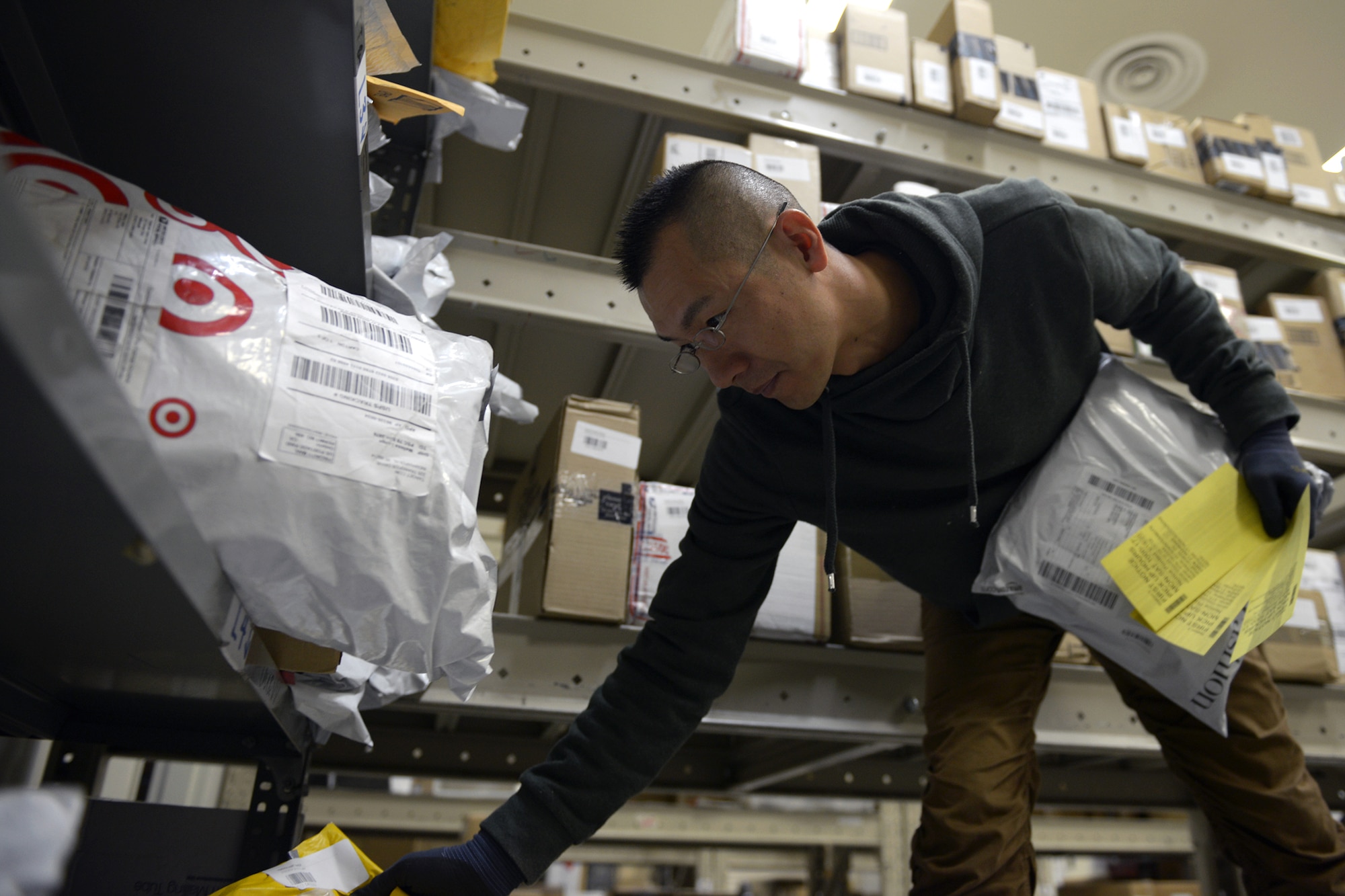 Akihito Mukawa, 374th Communications Squadron postal clerk, retrieves packages for pickup at Yokota Air Base, Japan, March 19, 2014. Packages and envelopes too large for personal mailboxes are sorted alphabetically to allow the clerks to find customers mail quickly and efficiently. (U.S. Air Force photo by Airman 1st Class David Danford/Released)