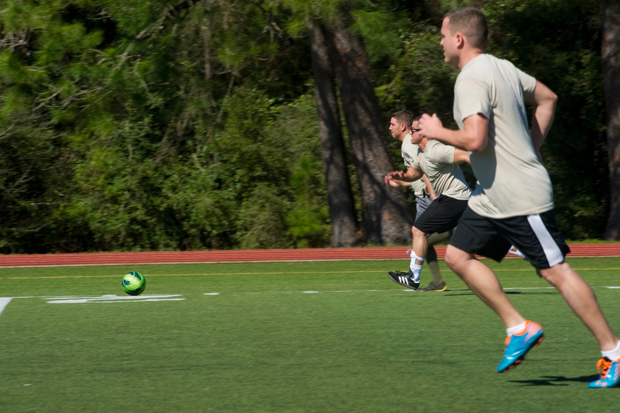 Airmen from Detachment 7, 373rd Training Squadron run toward a soccer ball during a match on the Aderholt Fitness Center field at Hurlburt Field, Fla., March 19, 2014. Men’s varsity soccer tryouts are slated for 9 a.m. to noon March 29, 2014 at the Aderholt. (U.S. Air Force photo/Senior Airman Naomi Griego)