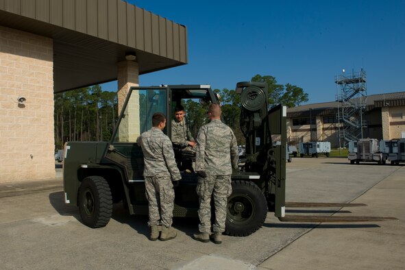 Airmen from the 1st Special Operations Logistics Readiness Squadron vehicle operations section prepare to lift an aircraft stand and tow bar on a trailer on the flightline at Hurlburt Field, Fla., March 20, 2014. The 1st SOLRS vehicle operations section provides transportation to the entire base populace. (U.S. Air Force photo/Senior Airman Naomi Griego)