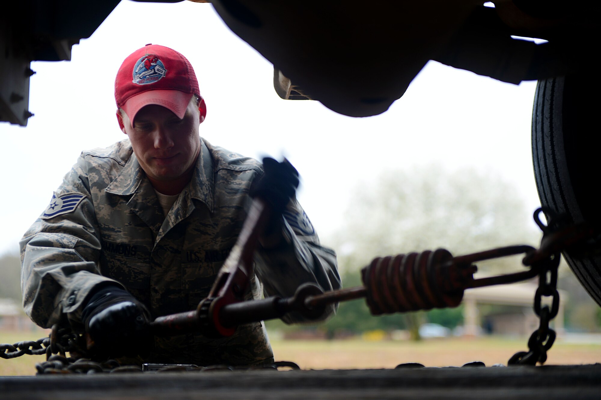 U. S. Air Force Staff Sgt. Mark Simmons, 823rd RED HORSE pavement and equipment operator assigned to Hurlburt Field, Fla., loosens a binder attached to a truck bed at Shaw Air Force Base, S.C., March 18, 2014. Simmons prepared several pieces of heavy equipment to be unloaded in preparation for the start of road paving project. (U.S. Air Force photo by Airman 1st Class Jensen Stidham/Released)