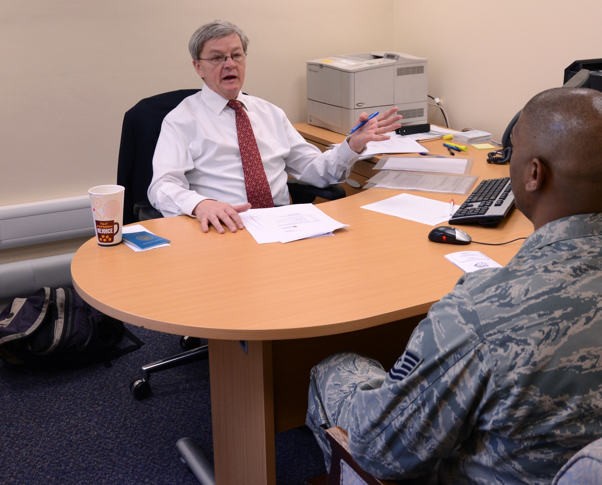 Michael Yebernetsky, left, Embassy of the United States of America overseas adjudication specialist from Madera, Penn., speaks with U.S. Air Force Tech. Sgt. Calvin Schroeder, 100th Logistics Readiness Squadron NCO in charge of flight service center from Oxon Hill, Md., about the process of getting a visa March 20, 2014, at the Airman and Family Readiness Center on RAF Mildenhall, England. Two members of the U.S. Embassy visited RAF Mildenhall to provide naturalization, citizenship, visa and green card assistance to service members and their families. The two-day schedule has more than 70 appointments already booked, but the A&FRC is accommodating walk-ins. For more information contact the A&FRC at DSN 238-3406 or commercial at 01638 543406. (U.S. Air Force photo by Airman 1st Class Kelsey Waters/Released)