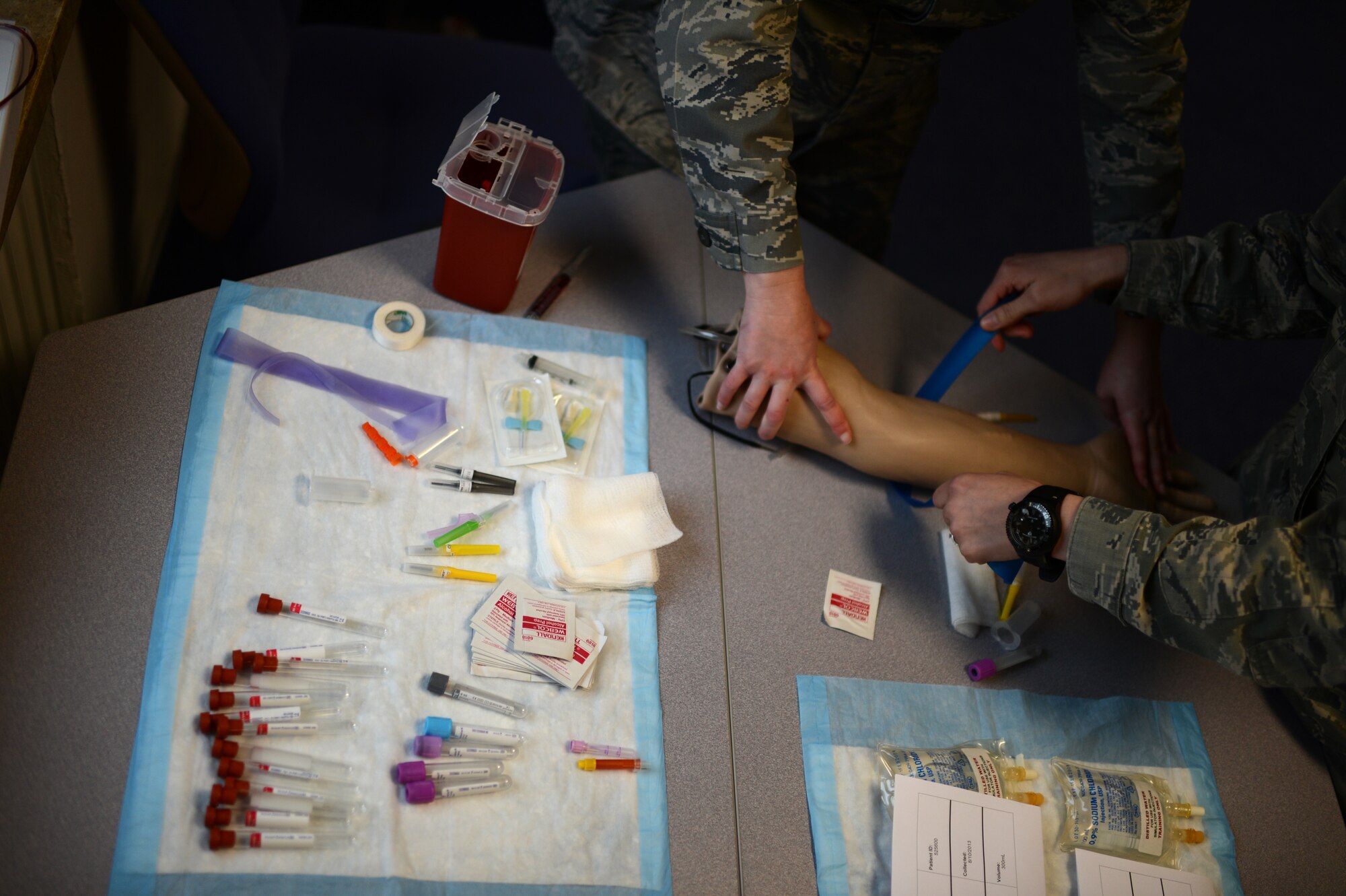 U.S. Air Force 1st Lt. Christen Chandler, 52nd Medical Operations Squadron family health clinical nurse from Kensington, Ohio, left, instructs U.S. Air Force Senior Airman Jaryl Burjoss, 52nd MDOS allergy immunization technician from Mooresville, N.C., on blood specimen collection procedures during a skills training class March 19,2014 at Spangdahlem Air Base, Germany. The training is designed to give medical technicians hands-on experience so Airmen can stay proficient with life-saving skills. (U.S. Air Force photo by Senior Airman Gustavo Castillo/Released)