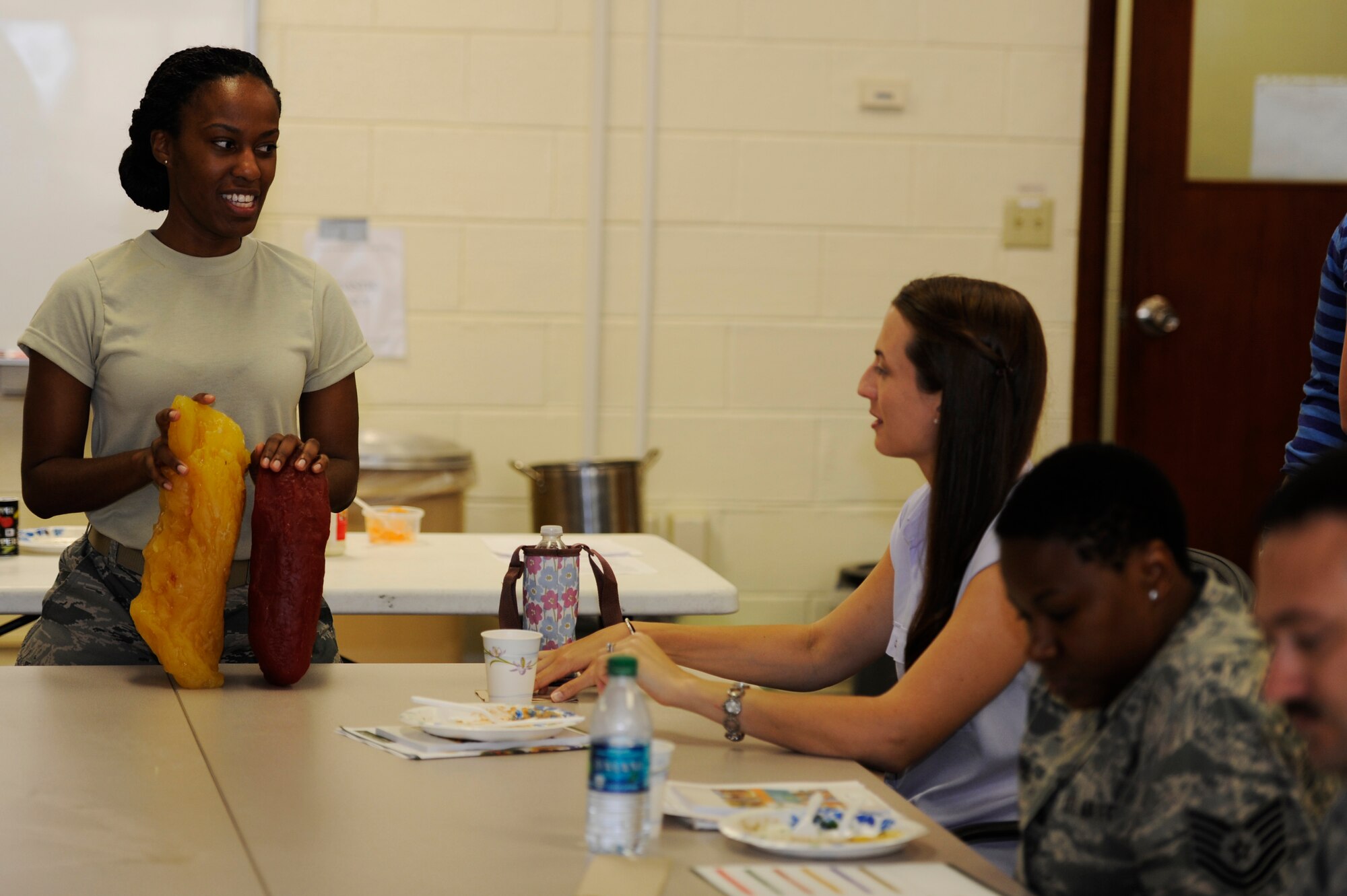 U.S. Air Force Tech. Sgt. Jennifer Randolph, 18th Aerospace Medicine Squadron diet technician, shows the difference in five pounds of fat versus five pounds of muscle to Airmen during a healthy cooking demonstration at the Health and Wellness Center on Kadena Air Base, Japan, March 19, 2014. Randolph said the average person consumes 146 to 160 pounds of sugar annually, when they only nutritionally need 10 teaspoons of sugar for men and six teaspoons for women daily. (U.S. Air Force photo by Senior Airman Marcus Morris)