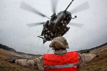 A landing support specialist with Combat Logistics Regiment 2, 2nd Marine Logistics Group, II Marine Expeditionary Force gives hand and arm signals to a CH-53E Super Stallion from Marine Heavy Helicopter Squadron 461, Marine Aircraft Group 29, Marine Corps Air Station New River, during a Helicopter Support Team exercise at Davis Airfield aboard Camp Lejeune, N.C., March 19, 2014. Marines with CLR-2 were hooking a M777 howitzer to the Super Stallion. 