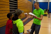 A Marine volunteer with General Support Maintenance Company, 2nd Maintenance Battalion, 2nd Marine Logistics Group teaches area children how to make paper airplanes during a science fair in Jacksonville, N.C., March 15, 2014. Thirty Marines with the company volunteered time during their weekend at several locations throughout the area as a way to give back to the community that surrounds Marine Corps Base Camp Lejeune, N.C.