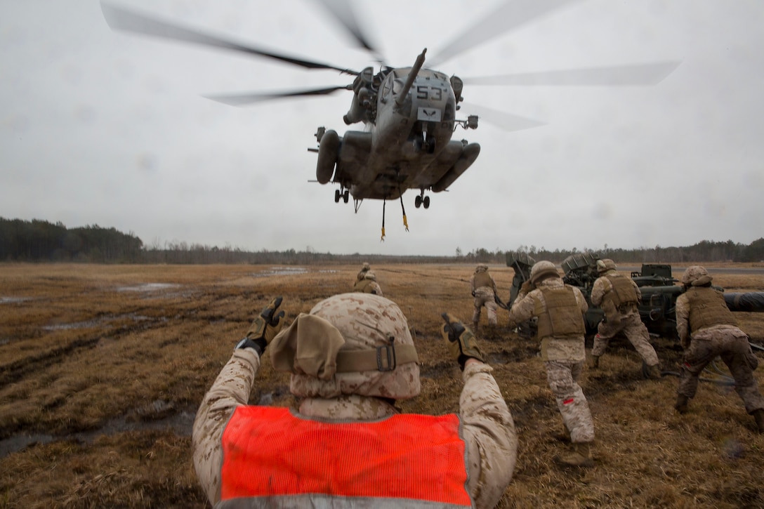 A landing support specialist with Combat Logistics Regiment 2, 2nd Marine Logistics Group, II Marine Expeditionary Force gives hand and arm signals to a CH-53E Super Stallion from Marine Heavy Helicopter Squadron 461, Marine Aircraft Group 29, Marine Corps Air Station New River, during a Helicopter Support Team exercise at Davis Airfield aboard Camp Lejeune, N.C., March 19, 2014. 1st Battalion, 10th Marine Regiment brought two M777 howitzers for 2nd MLG Marines to train with.