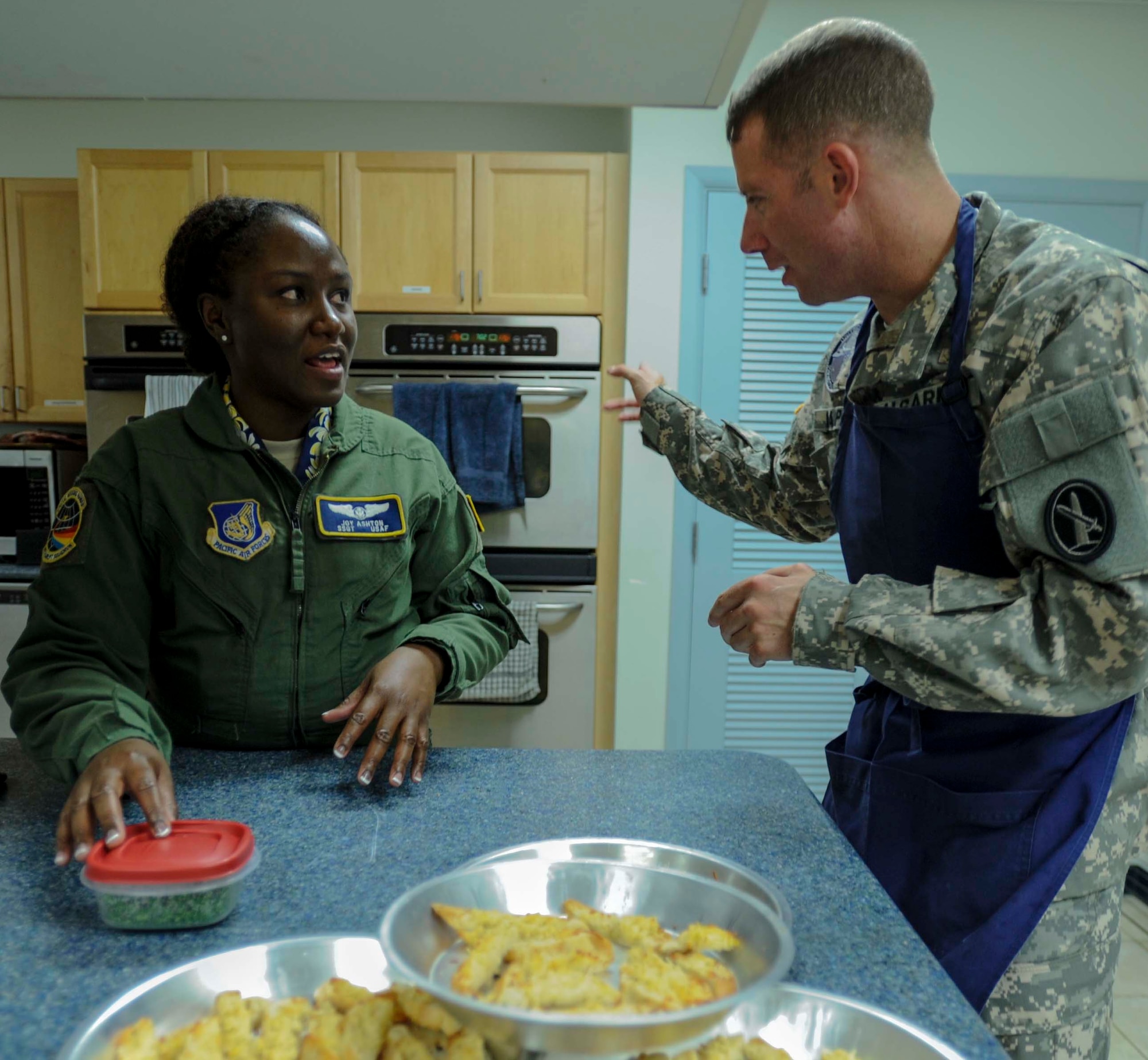 Staff Sgt. Joy Ashton, 65th Airlift Squadron flight attendant, listens carefully as Army Staff SGT. Steve Harper Jr., U.S. Army Priority Air Detachment flight steward, explains the proper oven settings used to make a crostini at the 65th AS flight kitchen on Joint Base Pearl Harbor-Hickam, Hawaii, March 19, 2014. The dish will be served as part of a seven-course Joint Service Flight Culinary Training Meal. The flight culinary training meals are part of an ongoing effort between the two services to maximize on-the-job training opportunities and increase camaraderie and cross-flow of communication between the units. (U.S. Air Force photo/Tech. Sgt. Terri Paden)