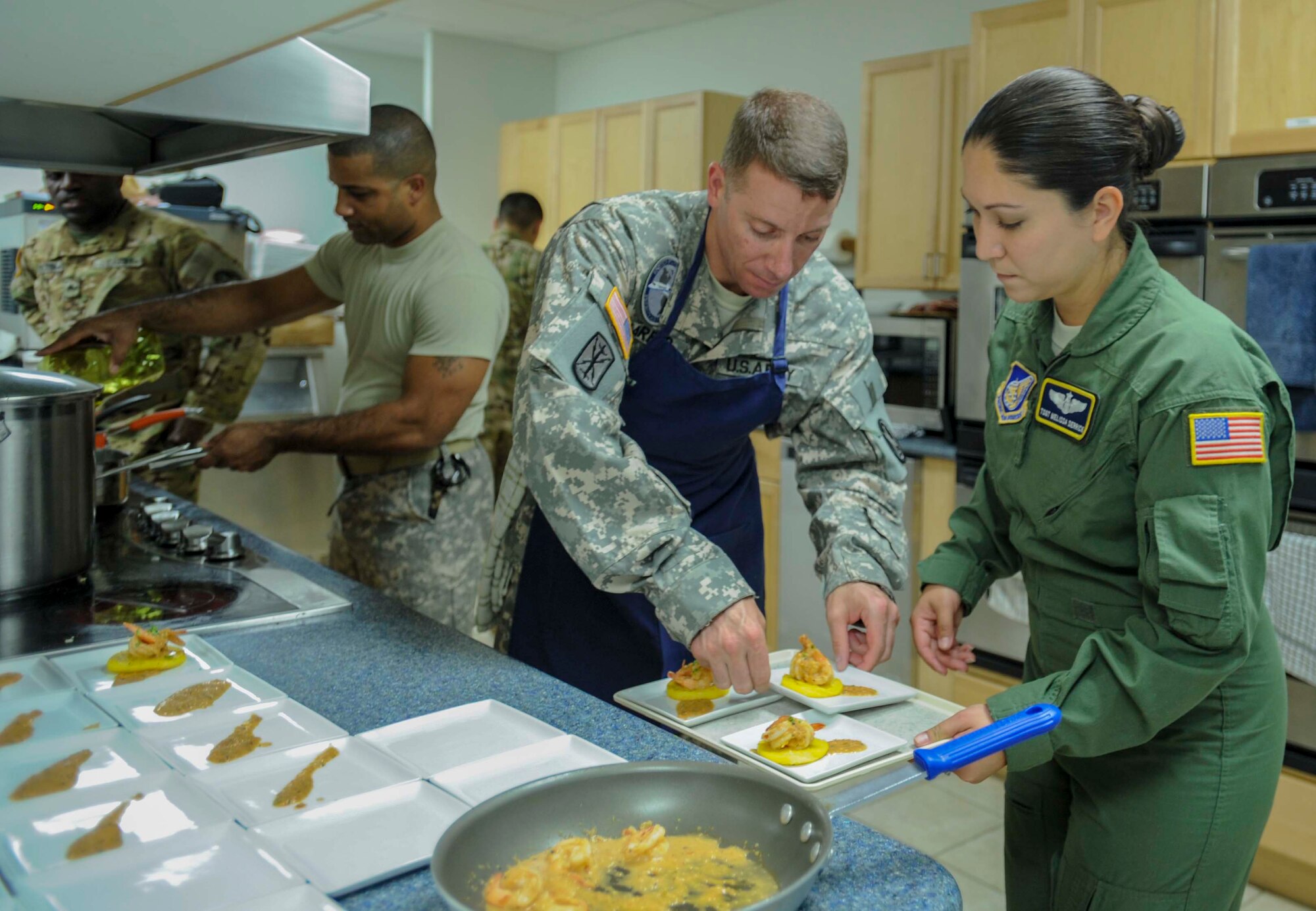 Army Staff SGT. Steve Harper, Jr., U.S. Army Priority Air Detachment flight steward, assists Tech. Sgt. Melissa Derrick, 65th Airlift Squadron flight attendant, with placing shrimp and polenta appetizers on a serving tray in the 65th AS flight kitchen on Joint Base Pearl Harbor-Hickam, Hawaii, March 19, 2014. The appetizers will be served as part of a seven-course Joint Service Flight Culinary Training Meal. The flight culinary training meals are part of an ongoing effort between the two services to maximize on-the-job training opportunities and increase camaraderie and cross-flow of communication between the units. (U.S. Air Force photo/Tech. Sgt. Terri Paden)