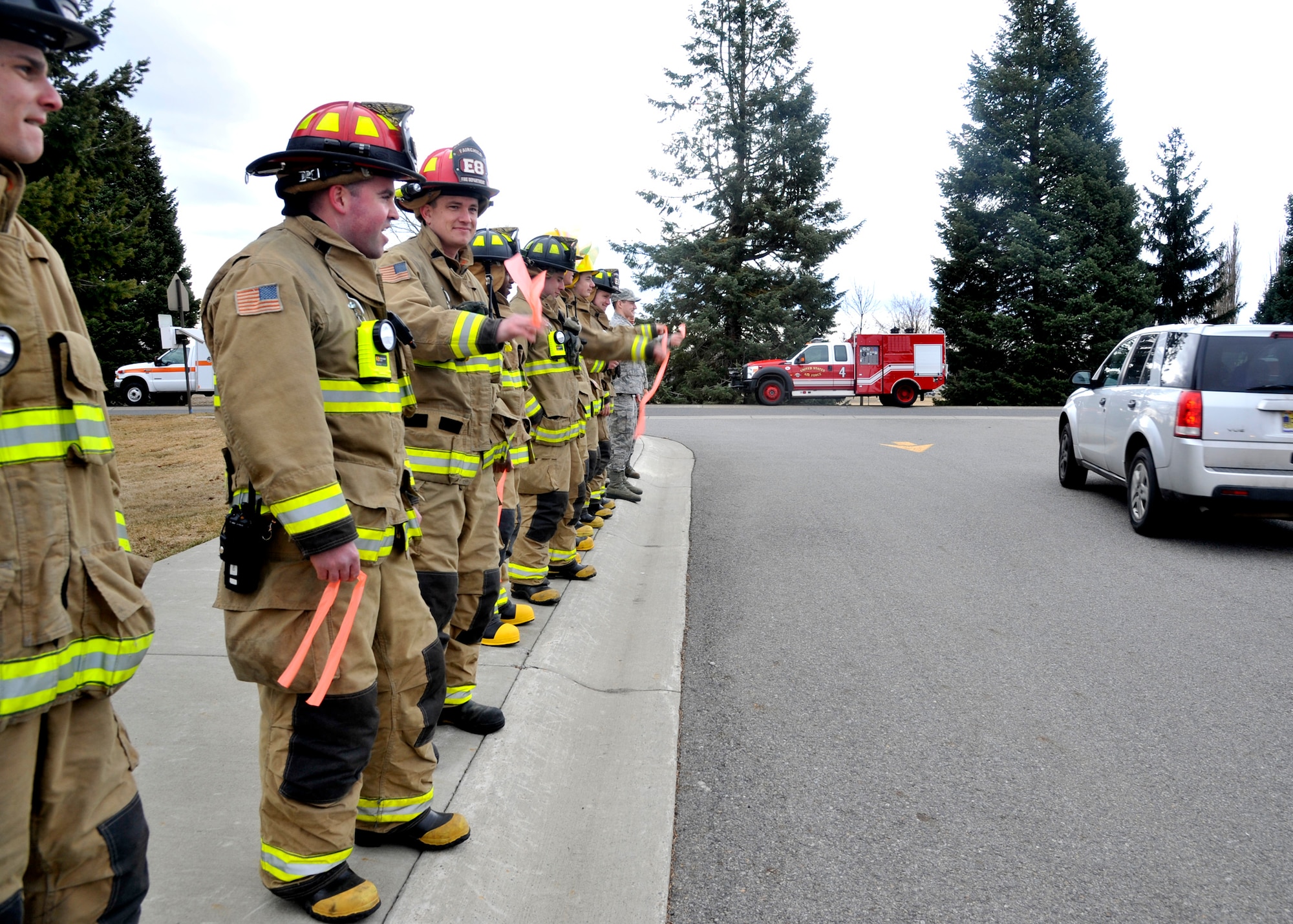 Members of the 92nd Civil Engineer fire department wave as London Bowater and her family drive by at Michael Anderson Elementary school on Fairchild Air Force Base, Wash., March 19, 2014. London has acute lymphoblastic leukemia and is traveling to Seattle to begin treatments after searching for a bone-marrow donor. (U.S. Air Force photo by Senior Airman Mary O'Dell/Released)