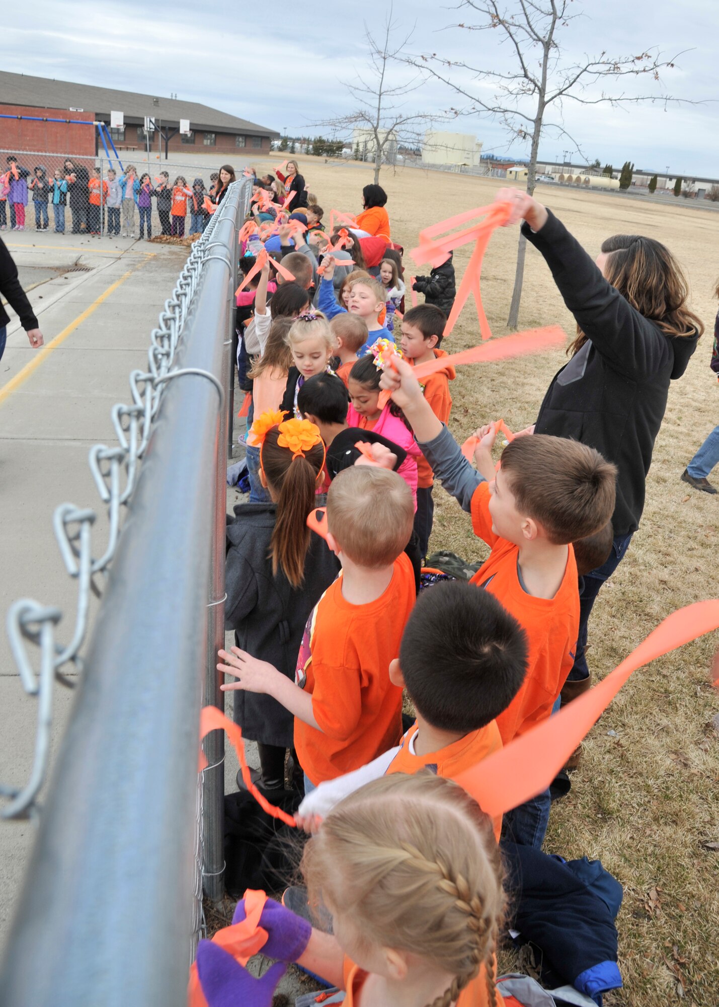Students from Michael Anderson Elementary school cheer and wave as the Bowater family drives through Fairchild Air Force Base, Wash., March 19, 2014. London Bowater, a MAE first-grader diagnosed with acute lymphoblastic leukemia, was just six months away from completing treatment when her family received word the cancer had returned. The Bowaters are traveling to Seattle to begin treatment again after searching for a bone marrow donor. (U.S. Air Force photo by Senior Airman Mary O'Dell/Released)