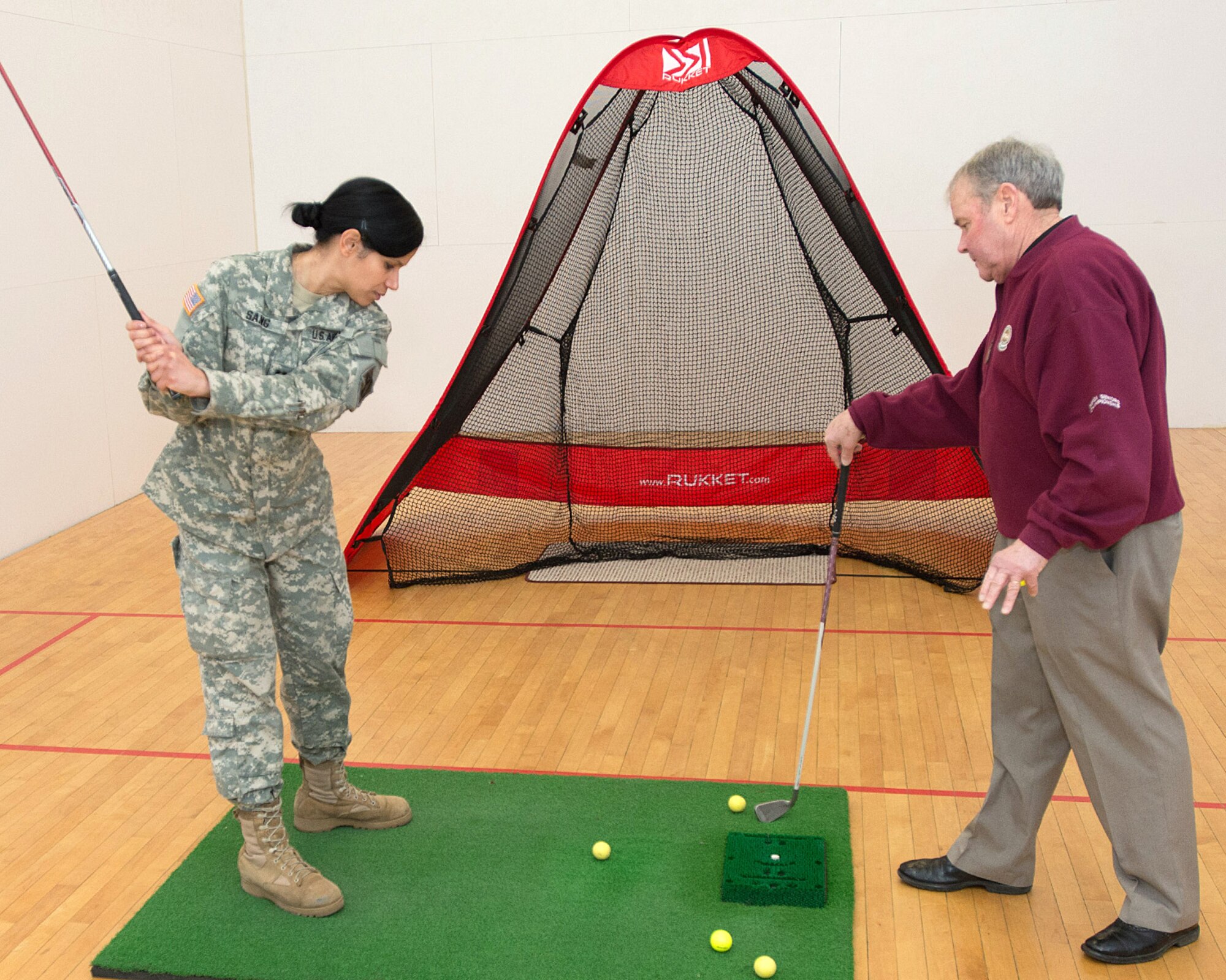 HANSCOM AIR FORCE BASE, Mass. – Massachusetts Army National Guard Capt. Tania Sang participates in a golf-swing lesson from Jim Tobin, the Patriot Golf Course manager, at the Health and Fitness Expo at the Hanscom Fitness Center March 19. The Fitness Center hosted a number of health and wellness vendors, information booths and demos. (U.S. Air Force photo by Rick Berry)