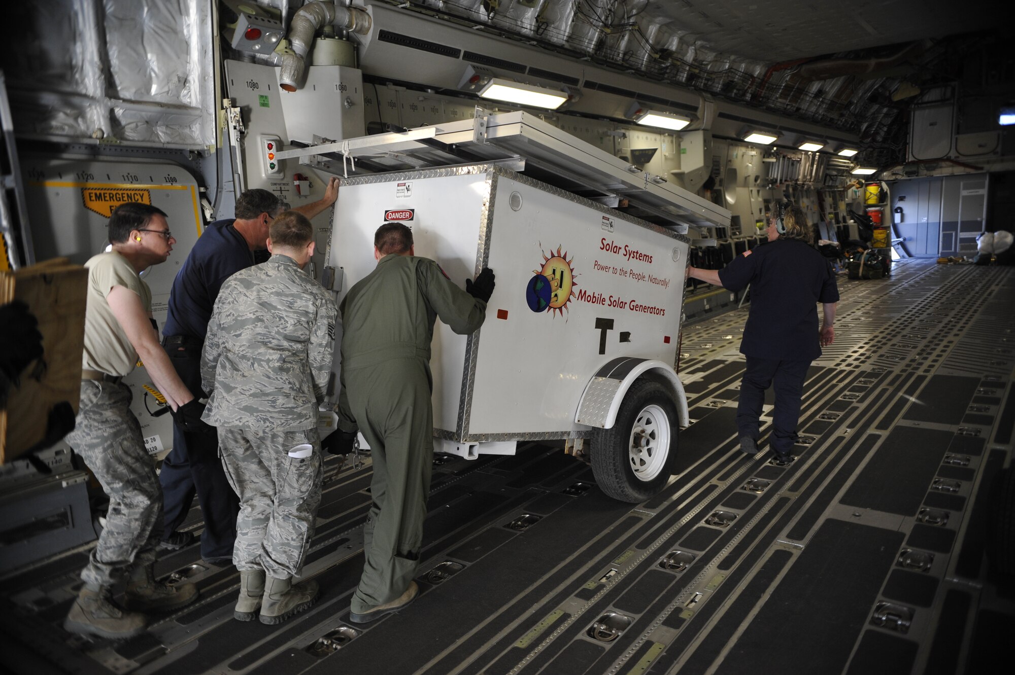 Airmen from Luke Air Force Base and Altus AFB, Okla., push a solar generator up the C-17 aircraft ramp Monday on the flightline. (U.S. Air Force photo/Senior Airman David Owsianka)