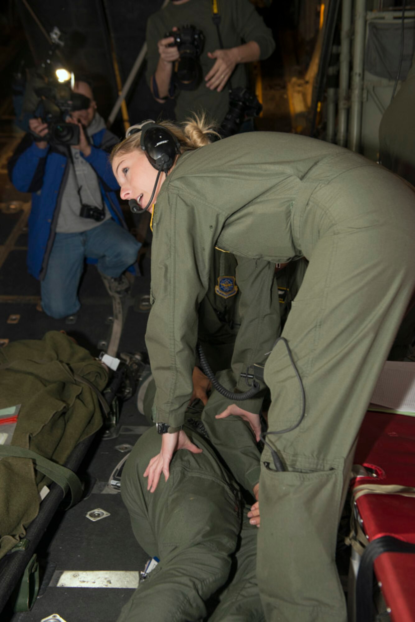 A crew member of the aeromedical crew has gone into seizure during the flight. The Aeromedical team jumps into action. Monitors and medications come into play as the flight nurses move to stabilize the patient. Simulated medical emergencies during training flights allow the team to practice in the close, tight environment. Capt. Sabrina Ruppe, a flight nurse checks the patient and calls for monitoring equipment. (Photo by Lewis Perkins/Paraglide)