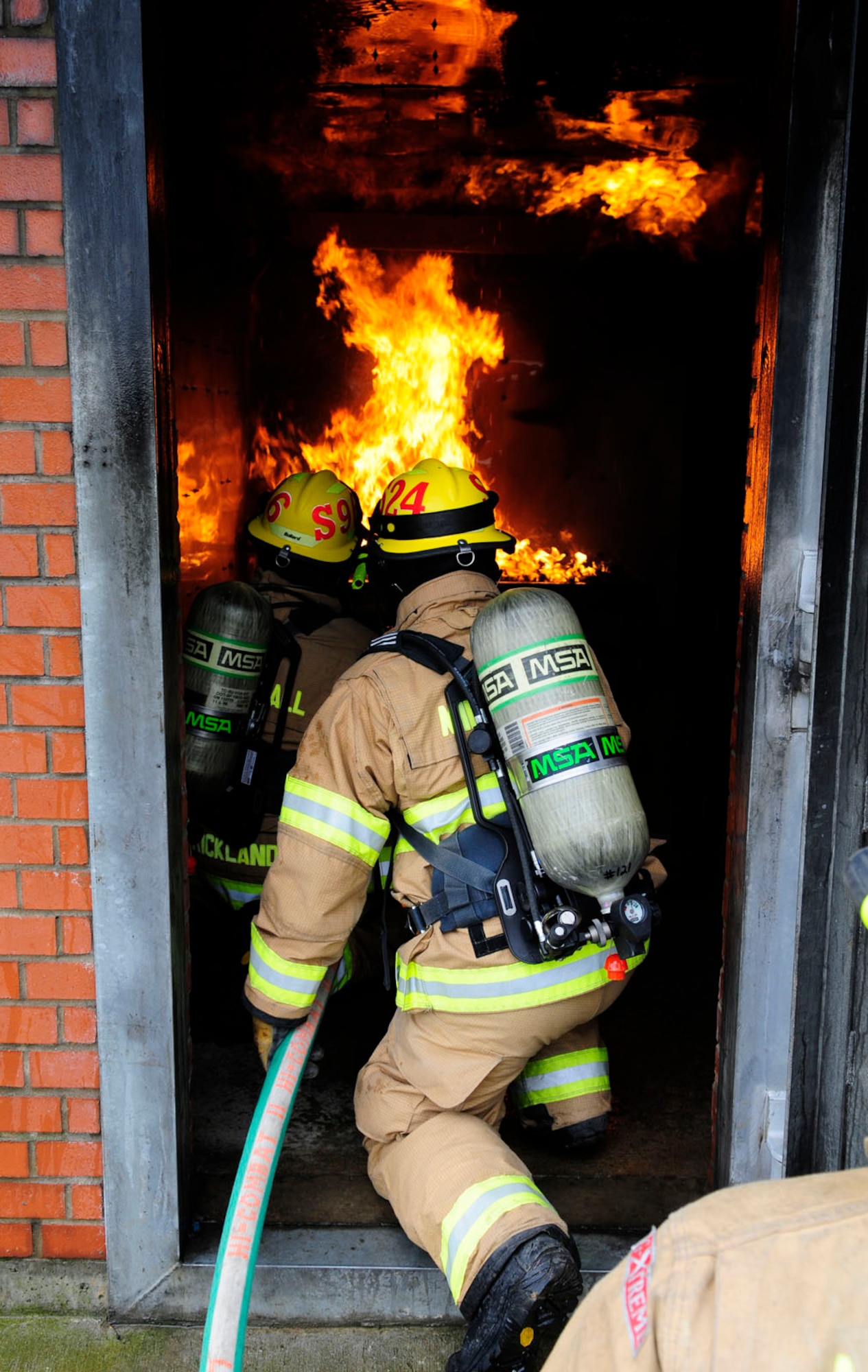 Defence Fire Service Firefighters Malcolm Strickland, left, from Ramsgate, Kent, and Steve Scales, from Broadstairs, Kent, both 100th Civil Engineer Squadron Fire Department firefighters, use a handline to practice extinguishing a fire March 18, 2014, in the structural trainer on RAF Mildenhall, England. RAF Mildenhall's firefighters are required to train on two structural and two aircraft live-fire burns per year, enabling them to learn and practice proper firefighting techniques. It also allows them recognize firsthand the importance of their personal protective equipment within a live-fire environment, as well as requirements to keep them as safe as possible while on scene. Using the structural trainer ensures using proper extinguishing techniques to prevent flashovers becomes second nature. (U.S. Air Force photo by Karen Abeyasekere/Released) 