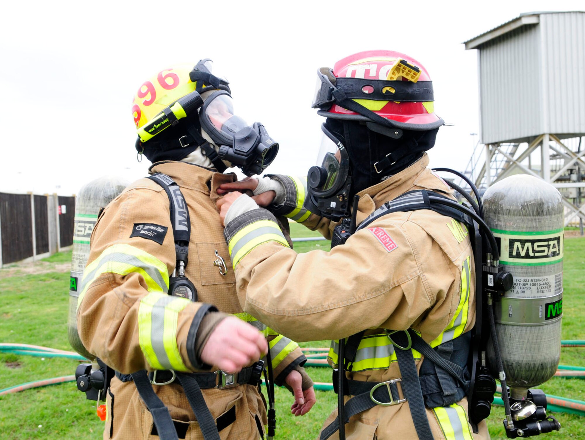 U.S. Air Force Staff Sgt. Minh Thlang, right, from Seattle, Wash., and Defence Fire Service Firefighter Malcolm Strickland, from Ramsgate, Kent, both 100th Civil Engineer Squadron Fire Department firefighters, conduct buddy checks March 18, 2014, during a live fire training exercise on RAF Mildenhall, England. Buddy checks are vital in ensuring their personal protective gear is not compromised, as firefighters place their lives in each other's hands and must be able to trust each other. Before entering a dangerous environment, it's routine for team members to check their partner's gear to prevent injury or death. This wingman principle is instilled in Air Force firefighters during technical school and continues throughout their career. (U.S. Air Force photo by Karen Abeyasekere/Released)