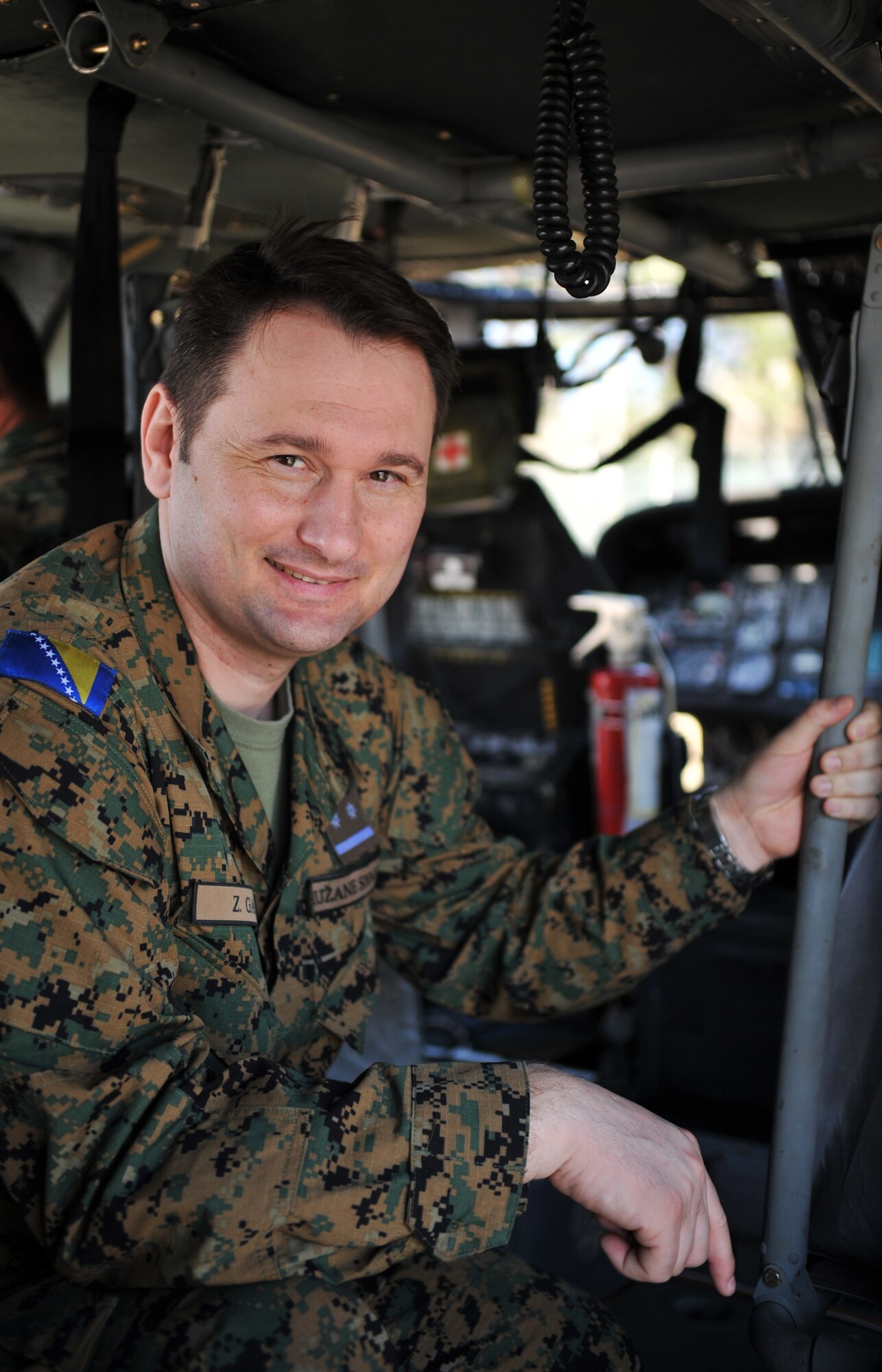 A Bosnian military member takes a moment to smile for a photo during a tour of a rotary wing aircraft as part of the Firefighters Fundamentals Course, March 12, 2014, at Landstuhl Regional Medical Center, Germany. The course consisted of hands-on simulations and classroom portions allowing service members to learn about different fire rescue techniques. (U.S. Air Force photo/Senior Airman Hailey Haux)