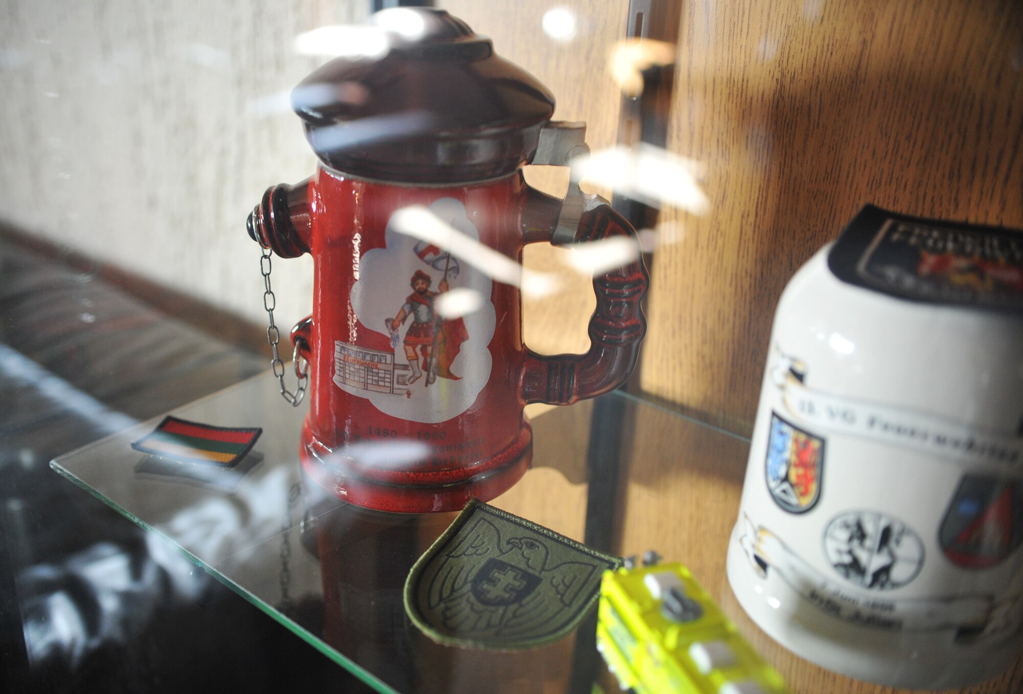 A Lithuanian crest and flag patch sit inside a trophy case next to other firefighting memorabilia March 12, 2014, at Ramstein Air Base, Germany. Lithuanian and Bosnian military members took a tour of the fire house as part of the week-long Firefighters Fundamental Course. (U.S. Air Force photo/Senior Airman Hailey Haux)