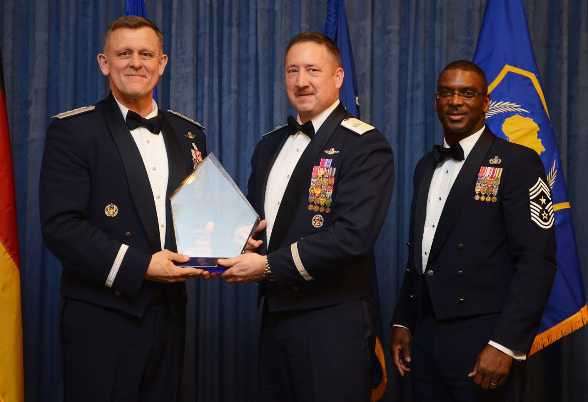 Brig. Gen. Jon Norman, 31st Fighter Wing commander, accepts the U.S. Air Forces in Europe and Air Forces Africa Honor Guard Program Manager of the Year award on behalf of Staff Sgt. Jimmy Farias, 31st Logistics Readiness Squadron fuels distribution supervisor, who has since moved back to the U.S., from Gen. Frank Gorenc, USAFE-AFAFRICA commander and Chief Master Sgt. James E. Davis, USAFE-AFAFRICA command chief, during an annual awards ceremony at Ramstein Air Base Germany March 20, 2014. The Airmen competed within their units, then at the wing level and have now been named the best in USAFE-AFAFRICA. They will go on to compete at the Air Force level for the coveted Outstanding Airmen of the Year award which will be announced later this year. (U.S. Air Force photo/ Staff Sgt. Ryan Crane)